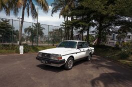 a white car parked in front of a fence